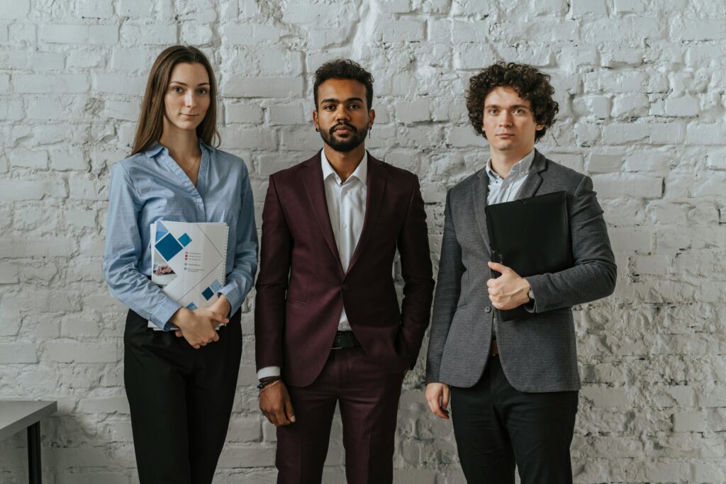 Three business professionals standing confidently in an office setting.